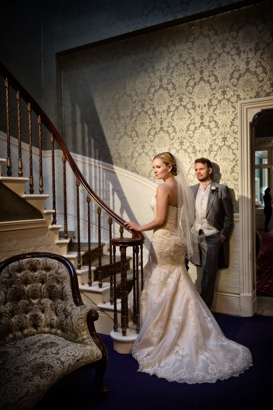 Bride and groom stand at the bottom of the main staircase at Penton Park