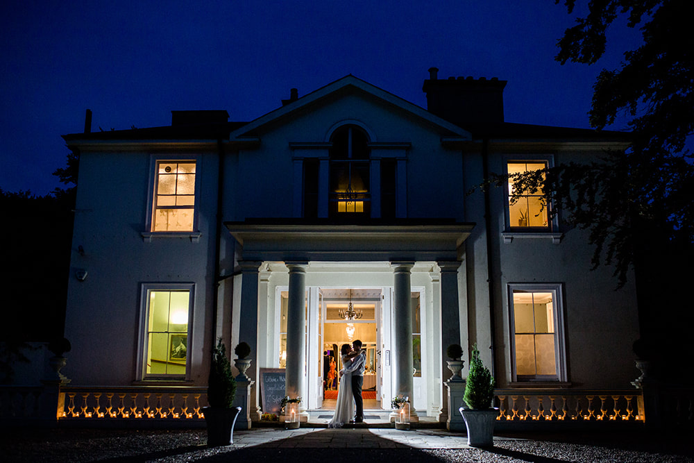 Beautiful night-time shot of the Portico at Penton Park, a private house wedding venue in north-west Hampshire, UK